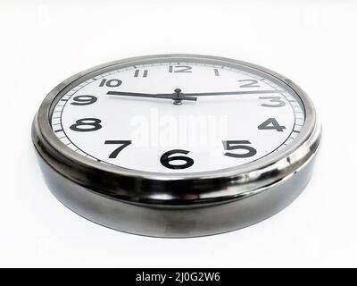 Analoge Uhr mit den Händen, die von unten an einer weißen Wand hängen. Zeitkonzept. Stockfoto