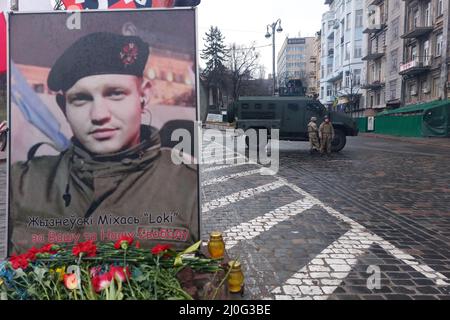 KIEW, UKRAINE 24. FEBRUAR. KIEW, UKRAINE - 24. FEBRUAR: Mitglieder der ukrainischen Sicherheitskräfte stehen Wache neben dem Denkmal für den weißrussischen geborenen Michail 'Loki' Zhyzneuski ( der einer der ersten Menschen war, die während der ukrainischen Revolution im Februar 2014 von der Bereitschaftspolizei getötet wurden ) Wie die Ukraine verhängte Kriegsrecht in der Stadt am 24. Februar 2022 in Kiew, Ukraine. Russland begann einen großen Angriff auf die Ukraine, nachdem das russische parlament Verträge mit zwei abtrünnigen Regionen in der Ostukraine gebilligt hatte. Stockfoto