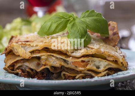 Lasagne mit Salat auf dunklem Holz Stockfoto