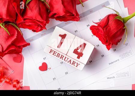 Valentinstag. Rote Feuerstellen und Rosen auf Kalenderseite. 14. Februar des Valentinstag. Rosa Hintergrund. Stockfoto