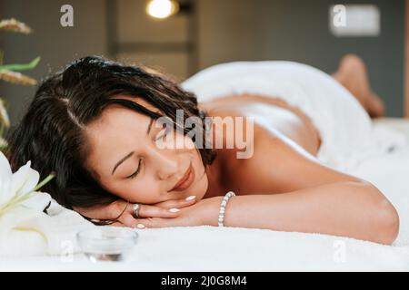 Schöne junge Frau im Massagesalon mit braunem lockiges Haar und gesunder Haut. Masseur und Patientenkonzept. Stockfoto