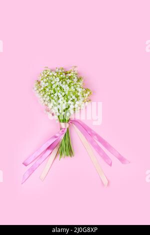 Bouquet von Maiglöckchen Blumen mit rosa Bändern auf einem rosa Hintergrund close-up Stockfoto