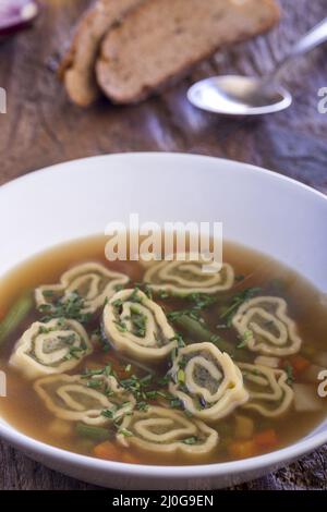 Bayerische Maultaschen Suppe auf Holz Stockfoto