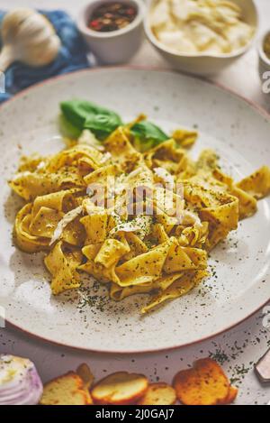 Gekochte hausgemachte Pasta mit Pesto, frischem Basilikum, Mozarella-Käse und Kräutern Stockfoto