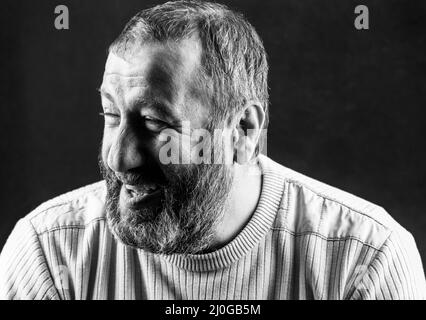 Porträt eines lächelnden grauen bärtigen Armeniers auf einem dunkelgrauen Schwarz-Weiß-Foto vor dem Hintergrund Stockfoto