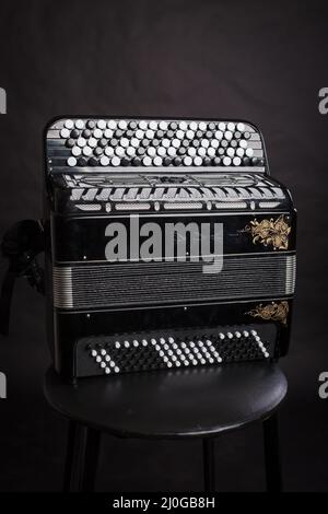 Russische Volksmusikinstrumente.Schwarzes Akkordeon isoliert auf dunklem Hintergrund Stockfoto
