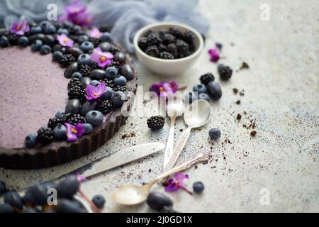 Süße und leckere Tarte mit frischen Heidelbeeren, Brombeeren und Trauben, serviert auf steinernem Hintergrund Stockfoto
