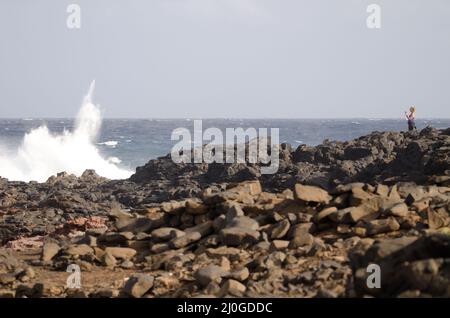 El Confital, 27. Februar 2022: Frau fotografiert eine Welle, die bricht. Las Palmas de Gran Canaria. Gran Canaria. Kanarische Inseln. Spanien. Stockfoto