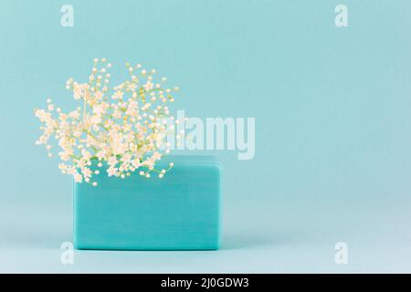 Ein Stück Seife handgefertigt mit kleinen weißen Blumen auf blauem Hintergrund mit einem Kopierraum Stockfoto