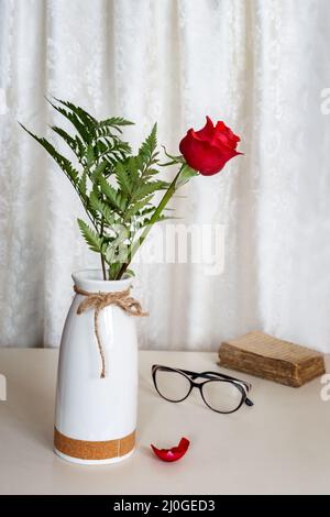 Rote Rose auf dem Tisch in einer Keramikvase Stockfoto