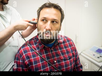 Arzt im Krankenhaus, der das Ohr des Patienten überprüft Stockfoto