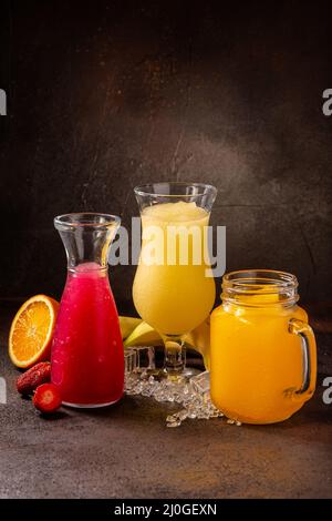 Leckere kalte erfrischende bunte Smoothie-Getränke in Cocktailglätten mit Früchten Stockfoto