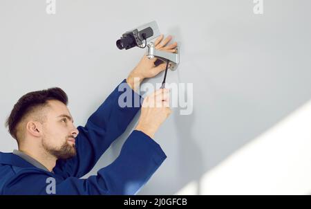 Ein Techniker installiert eine Überwachungskamera an der Wand Stockfoto