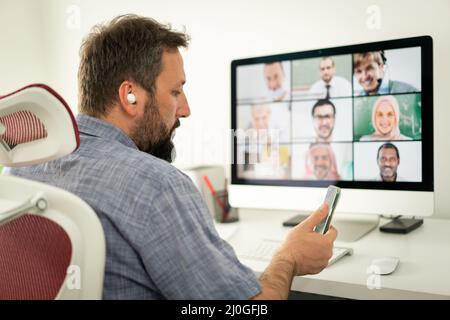 Mann mit mittlerem Erwachsenenalter, der eine Online-Konferenz von zu Hause aus hat Stockfoto