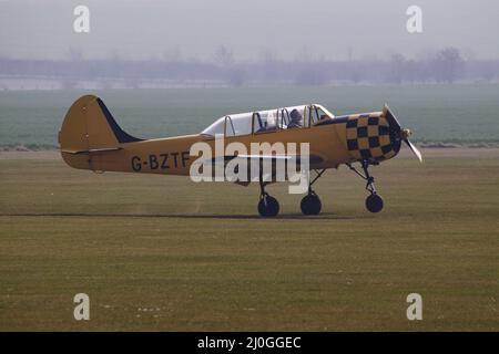 Ein gelber Yakovlev Yak 52, G-BZTF, der an einem nebligen Morgen abbricht Stockfoto