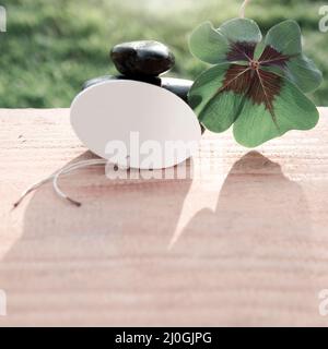 Schwarze Spa-Steine und vierblättriger Kleeblatt. Spa-Hintergrund. Stockfoto