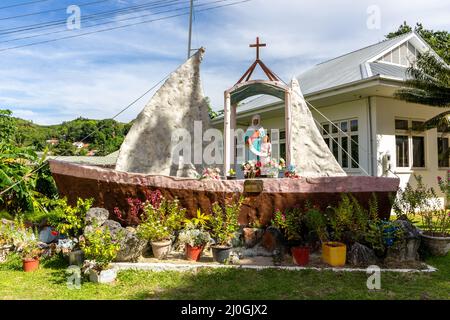 Statue der Sainte Anne von Praslin, die auf einer bootsförmigen Kapelle vor der katholischen St. Anne-Kirche in Baie Ste Anne, Praslin, Seychellen, steht. Stockfoto