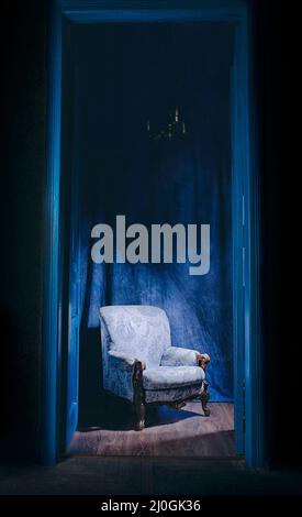 Leerer Sessel in Licht hinter blauen massiven Vintage-Türen im Innenbereich. Altmodisches Interieur-Konzept Stockfoto