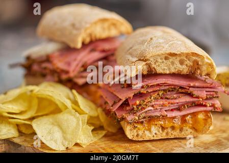 Pastrami-Sand, der sich mit köstlichen Speisen auf Baguette-Brot mit Käse, Zwiebel trifft Stockfoto