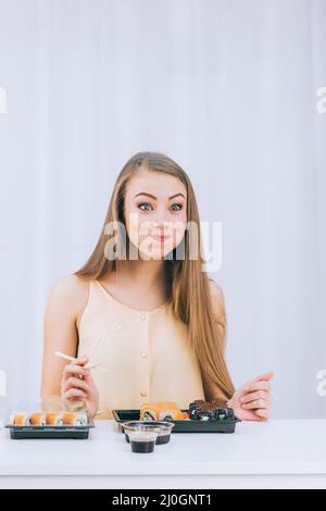 Ein lustiges Mädchen auf weißem Hintergrund probiert zum ersten Mal Sushi, Platz für Text Stockfoto