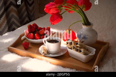 Erdbeeren auf einem Tablett mit Süßigkeiten und Kaffee, Blumen, festliches Frühlingsfrühstück, für Frauen Tag Stockfoto