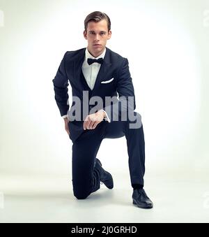Ein Gentleman-Outfit. Ein Studioporträt eines hübschen jungen Mannes in einem Vintage-Nadelstreifenanzug, der kniet. Stockfoto