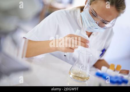 Sorgfältige, sorgfältige Arbeit. Eine junge Wissenschaftlerin, die in ihrem Labor ein Experiment durchführt. Stockfoto