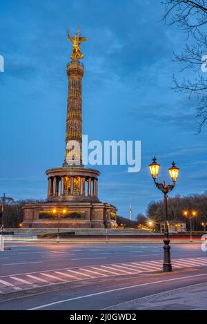 Die berühmte Siegessäule mit Straßenlaterne und Bäumen verzweigt sich in Berlin, Deutschland, in der Abenddämmerung Stockfoto