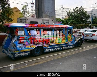 Ein farbenfroher Jeepney-LKW im Verkehr auf einer belebten Hauptstraße in Quezon City Stockfoto