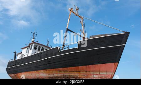 Alte Fischkutter an Land mit bewölktem Himmel Stockfoto