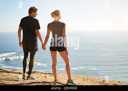 Genießen Sie die frische Luft und die spektakuläre Aussicht. Aufnahme eines jungen Paares, das die Aussicht von der Spitze eines Berges aus betrachtet. Stockfoto