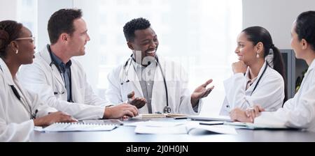 Ein Treffen medizinischer Köpfe. Ausgeschnittene Aufnahme einer Gruppe junger Ärzte, die sich im Sitzungssaal des Krankenhauses um einen Tisch treffen. Stockfoto