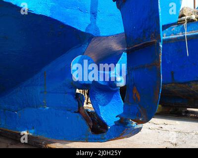 Der Propeller eines alten, blau rostigen Schiffes, das an einem sonnigen Tag auf trockenem Land steht Stockfoto