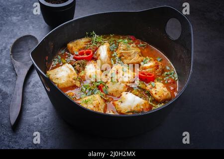 Traditionelle spanische Meeresfrüchte im modernen Stil, zarzuela de Pescado, mit Fisch in roter Sauce als Nahaufnahme in einem Design-Topf Stockfoto