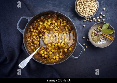 Traditioneller indischer Chana Masala-Eintopf mit Kichererbsen und Gewürzen, serviert von oben in Kochtöpfen Stockfoto