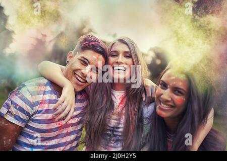 Regenbogen-Verfolger. Aufnahme von glücklichen Freunden, die Spaß mit Pulverfarbe haben. Stockfoto