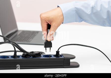 Nahaufnahme einer Frau die Hand stecken einen Stecker in eine Steckdose auf einem Tisch zu Hause Stockfoto