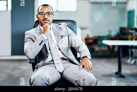 Ich habe große Ziele im Sinn. Ein Porträt eines hübschen jungen Geschäftsmanns, der in seinem Büro sitzt und mit der Hand auf dem Kinn nachdenklich aussieht. Stockfoto