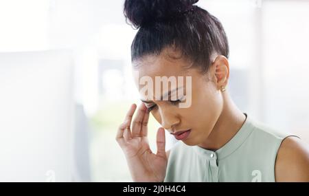 Nicht wieder diese Kopfschmerzen. Aufnahme einer attraktiven jungen Geschäftsfrau, die an Kopfschmerzen leidet, während sie an ihrem Schreibtisch in einem modernen Büro arbeitet. Stockfoto