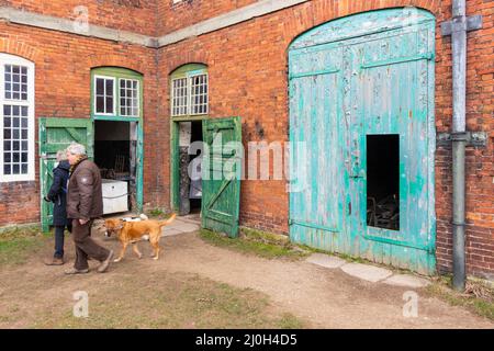 Besucher, die in den Stallungen von Calke Abbey Stables Tichnell Derbyshire in den verzweifelten grünen Stalltüren blicken Stockfoto