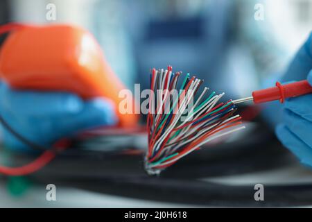 Mann, der Spannung mit Spezialausrüstung misst, Werkzeug zur Druckprüfung, Kabelbündel Stockfoto