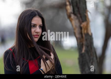 Ein Porträt einer charmanten, süßen Teenagerin, die nachdenklich aussieht und mit ihren langen Haaren spielt. Stockfoto