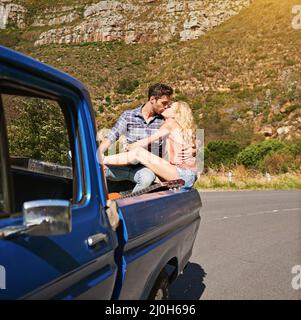 Reisen bringt Kraft und Liebe zurück in Ihr Leben. Aufnahme eines jungen Paares, das sich einen Kuss auf der Rückseite eines Pickup-Trucks teilt. Stockfoto