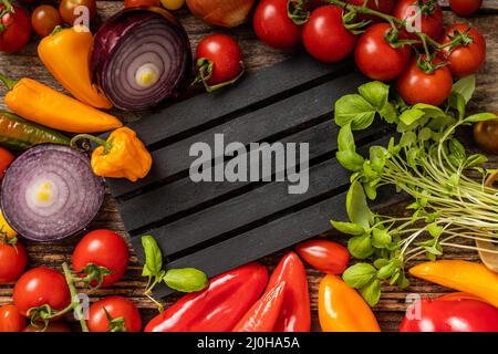 Auf der schwarz gestreiften Palette wird köstliches Gemüse serviert Stockfoto