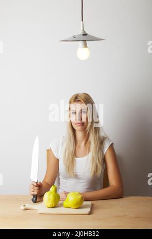 Attraktive junge blonde Frau mit einem Messer Stockfoto