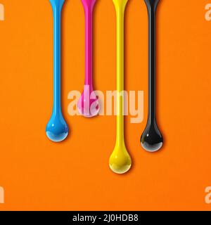 CMYCMY-Tintentropfen auf orangefarbenen quadratischen Papierhintergrund Stockfoto