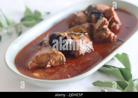 Makrelen-Currys im zentralen Kerala-Stil mit roten Chilischoten und Malabar-Tamarinde. Aufgenommen auf weißem Hintergrund. Stockfoto