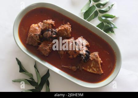 Makrelen-Currys im zentralen Kerala-Stil mit roten Chilischoten und Malabar-Tamarinde. Aufgenommen auf weißem Hintergrund. Stockfoto