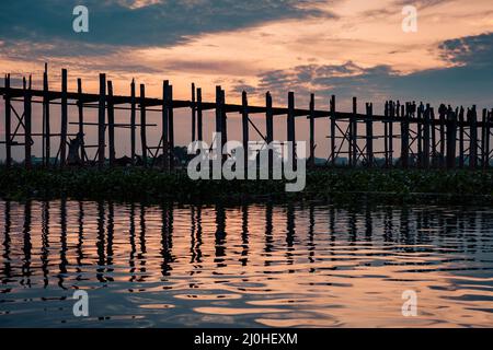 Person mit Silhouetten auf der U Bein Brücke bei Sonnenuntergang, Amarapura, Mandalay Region, Myanmar Stockfoto