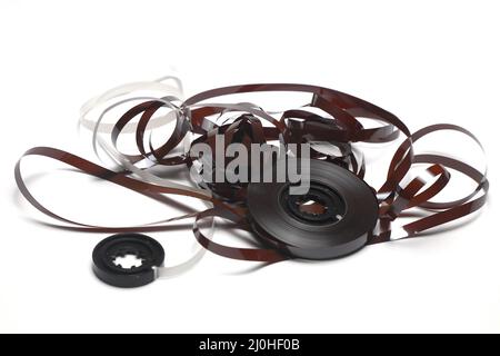 Alte Kassette mit aufgewickeltes Klebeband. Beschädigtes Datenträger für alte Tonaufnahmegeräte. Weißer Hintergrund. Stücke von einem alten Vintage-Kassettenband Stockfoto